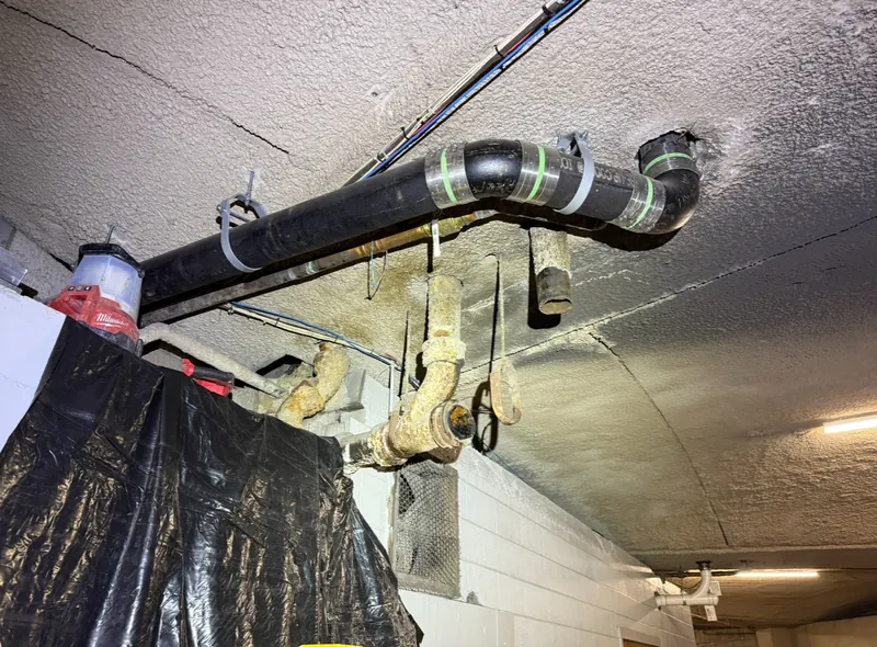 New no-hub cast iron drain line with banded couplings hung from a commercial ceiling