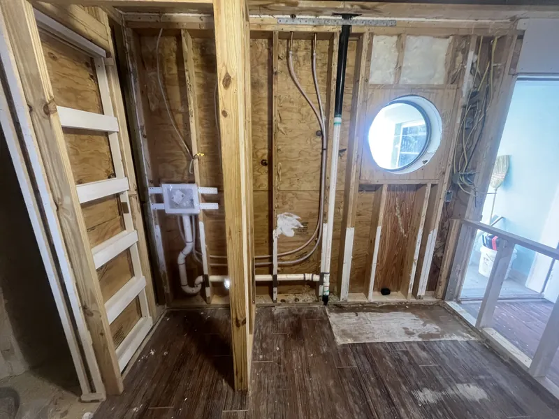Laundry and bar sink rough-in with washer box, supply and drain lines in open framing during a condo remodel