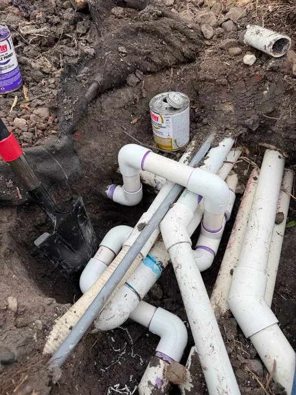 Complex PVC drain manifold with multiple fittings assembled in an excavated trench