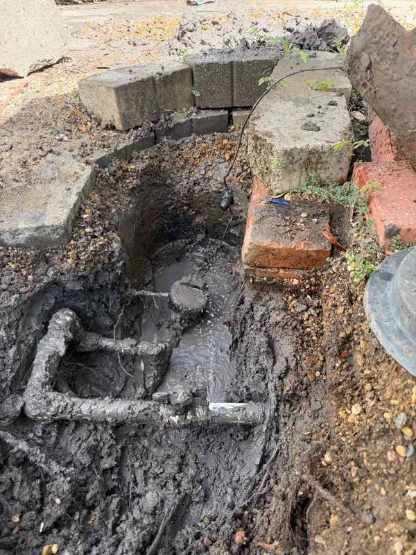 Deep excavation along a home foundation exposing a broken underground line