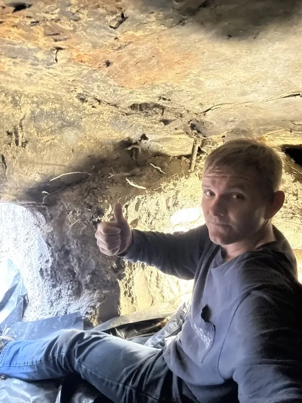 Plumber giving a thumbs up while working in a tight crawlspace