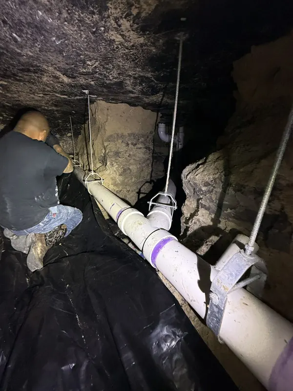 Large drain line supported with hangers through a crawlspace