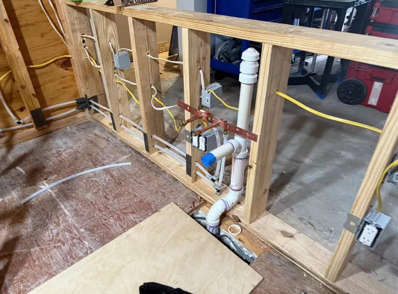 Washing machine outlet box with drain, vent and supply lines roughed into open studs