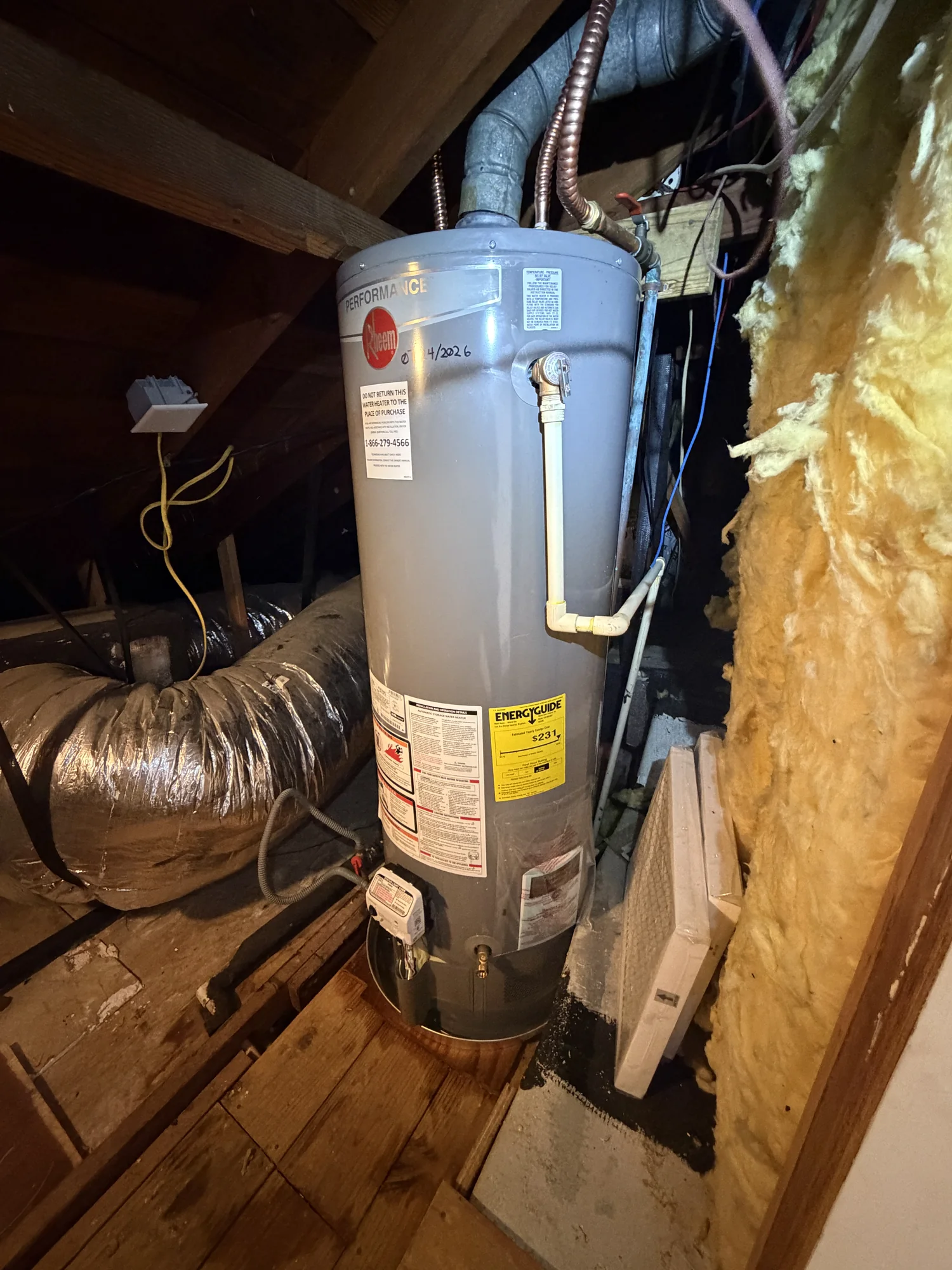 New gray Rheem Performance gas water heater installed in an attic with clean copper and gas connections